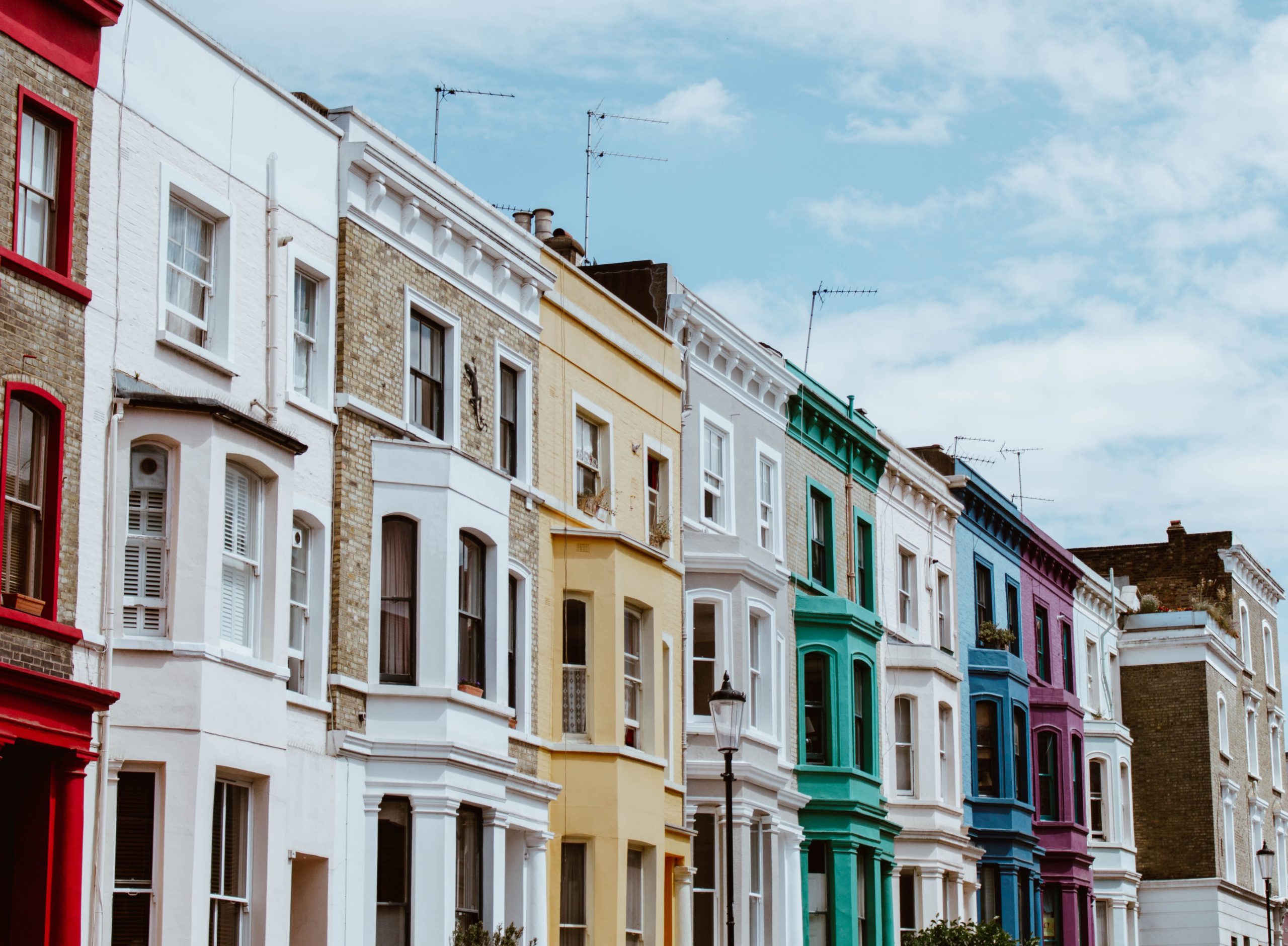 A row of terraced houses painted in different colours on a London street