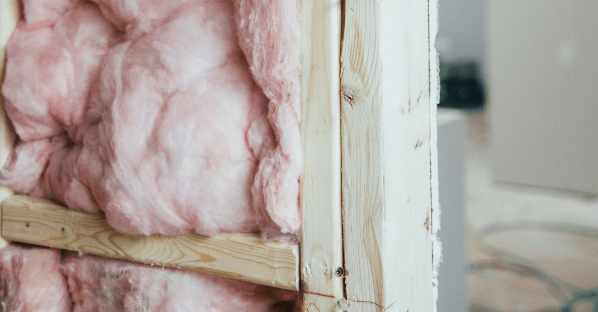 Photograph showing the inside of a wall within a home, filled with pink cavity wall insulation.